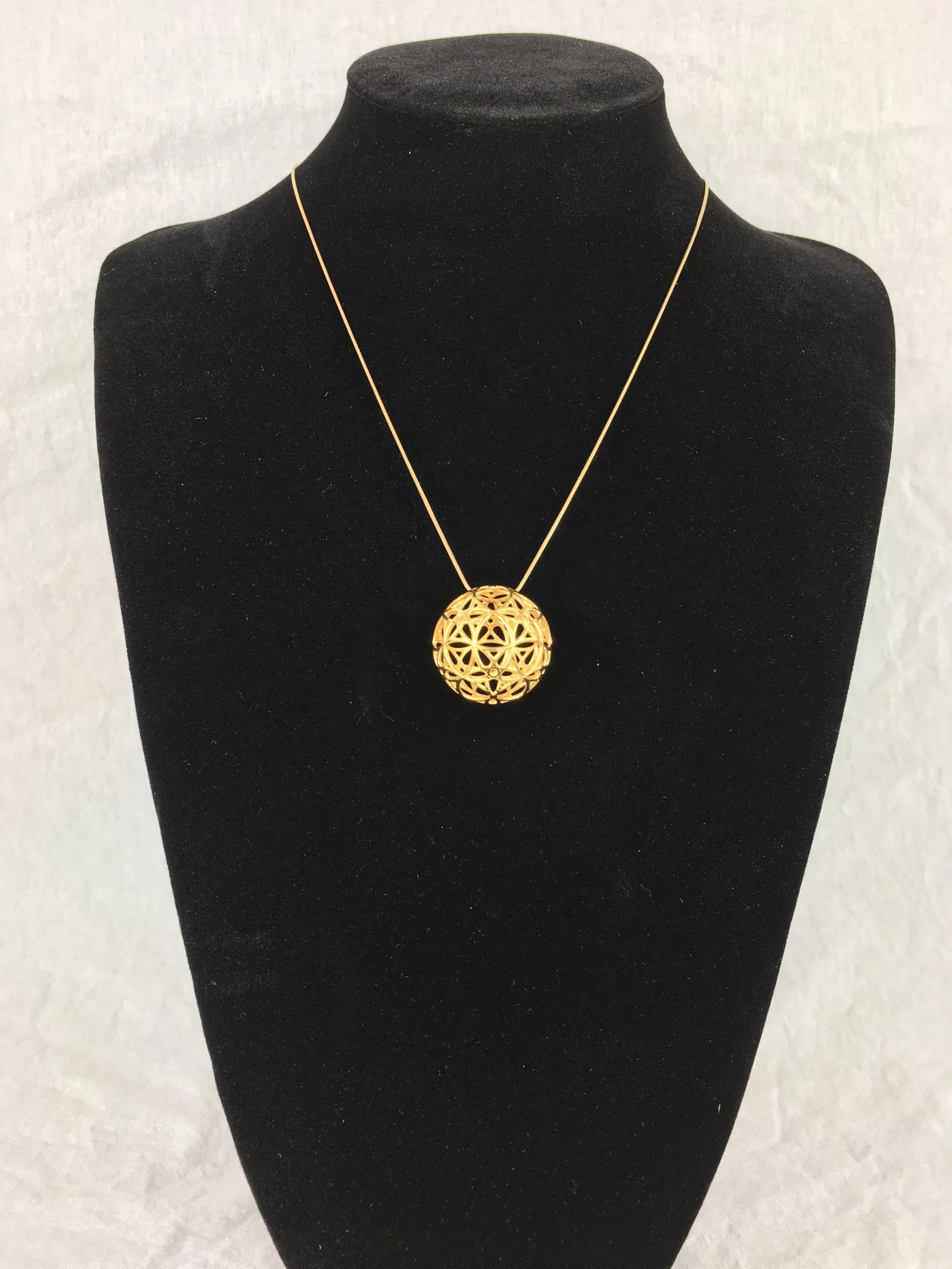 14k gold plated AllSphyr pendant on a gold chain displayed on a black necklace bust