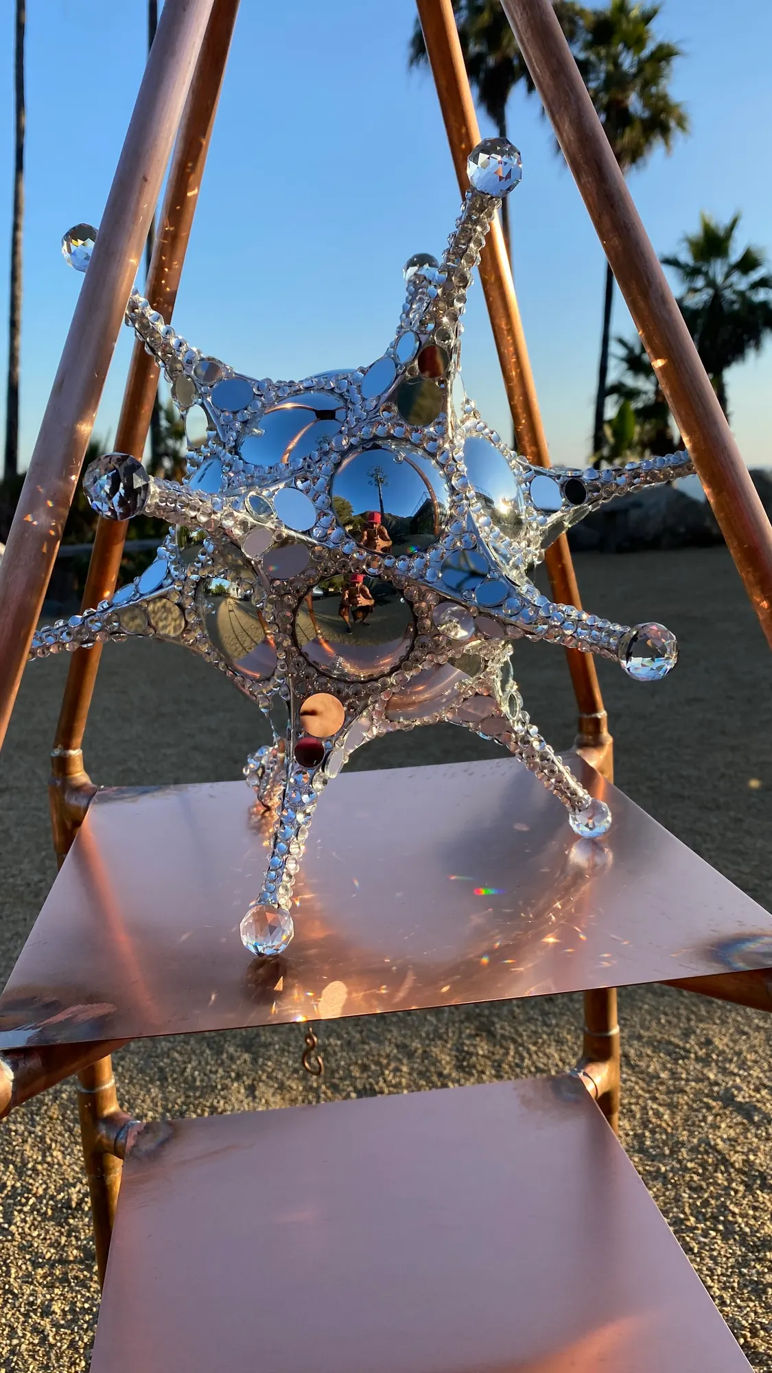 A mirrored star sculpture displayed on the copper shelf of the Pyramid Altar outdoors