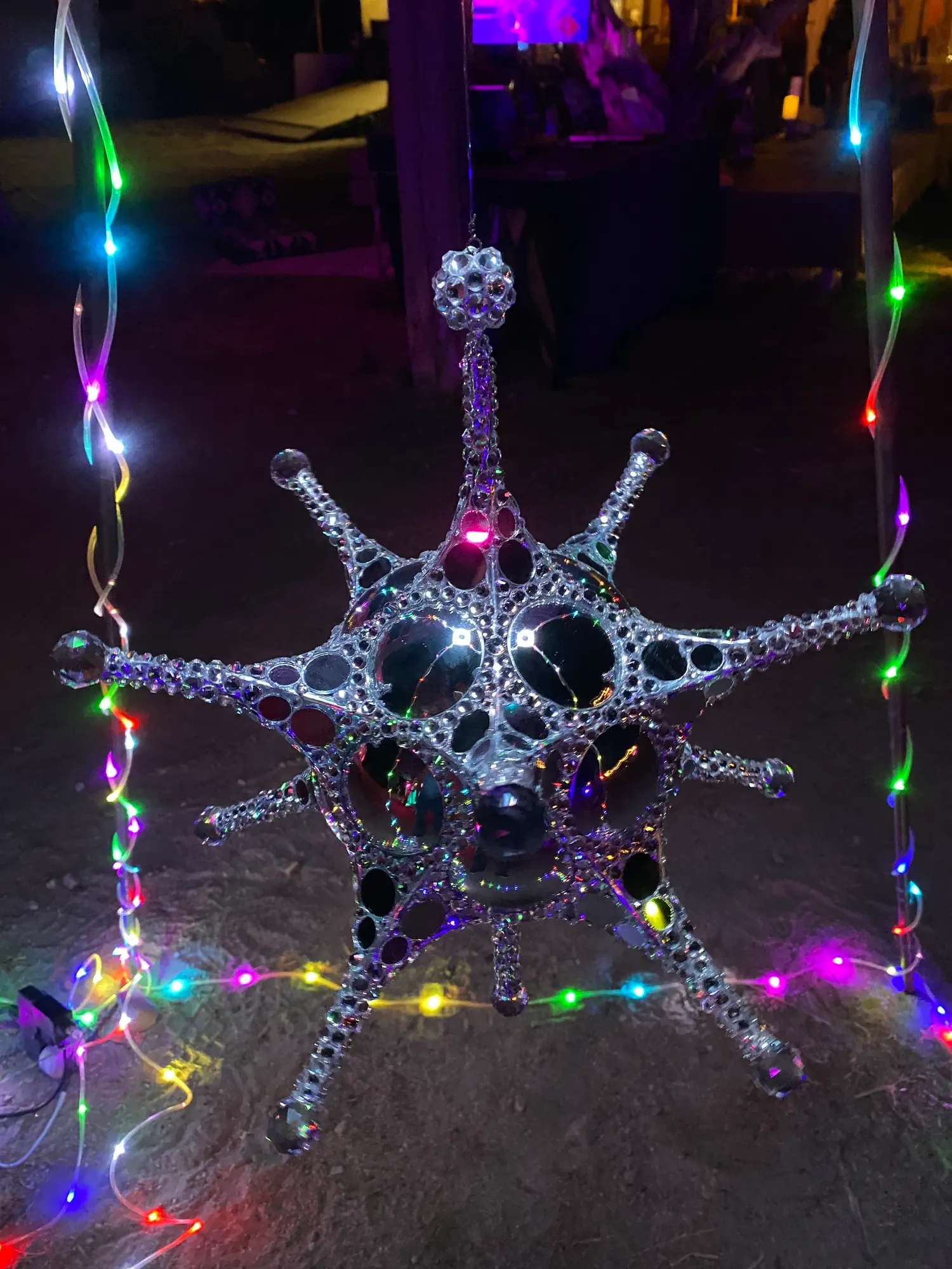 Metatron Reflections at night, its mirrors catching multicolored event lighting
