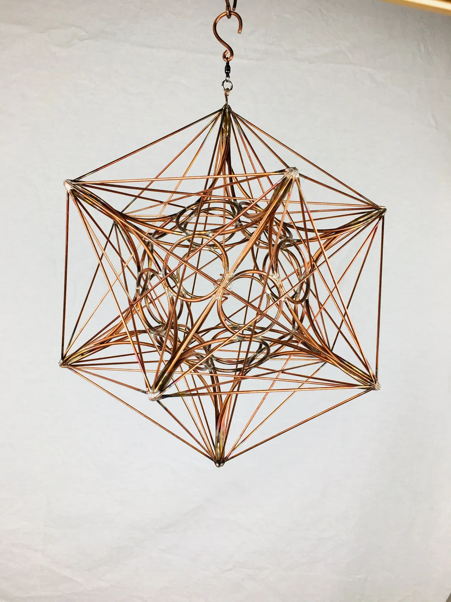Metatron's Cube: a hanging copper wire sculpture of intersecting rings inside a star-shaped frame, on a white background