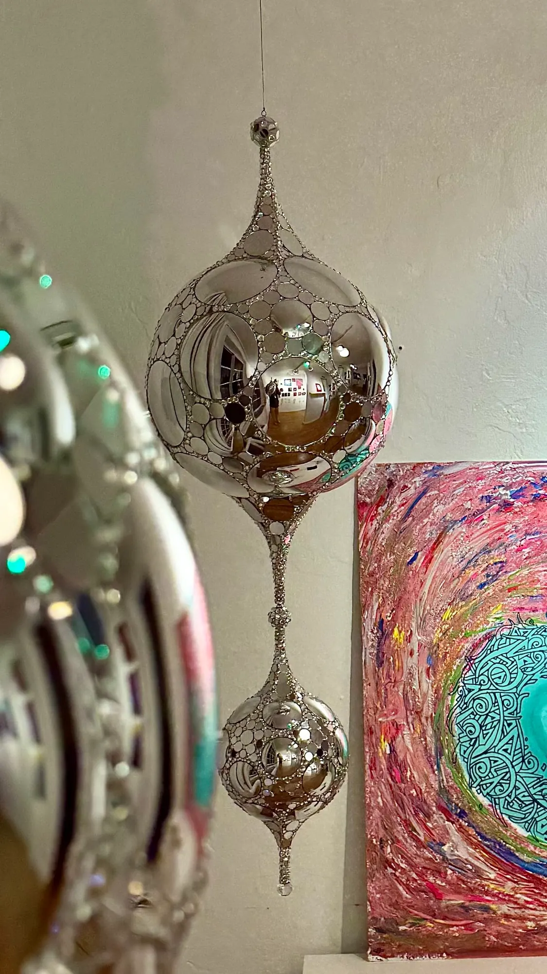 Teardrop DiscoSphyr hanging beside a colorful abstract painting in a gallery