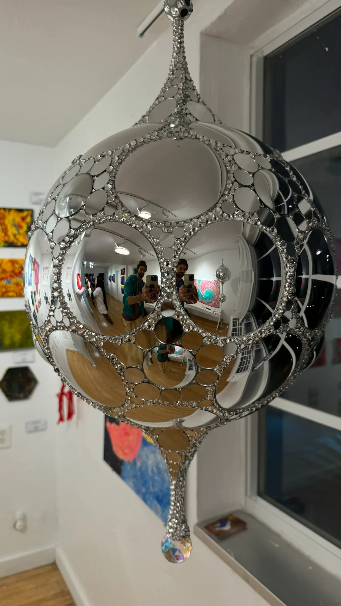 Close view of the Galactic DiscoSphyr's convex mirrors and rhinestone seams reflecting a gallery interior